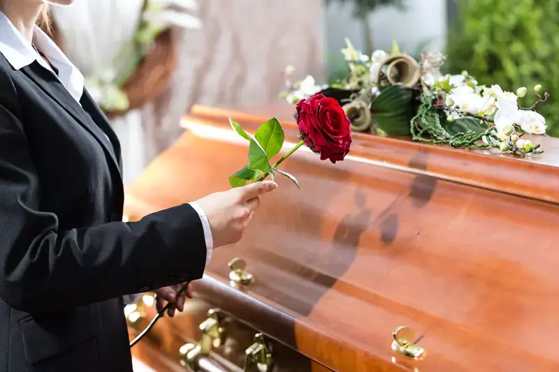 femme qui pause une fleur sur un cercueil