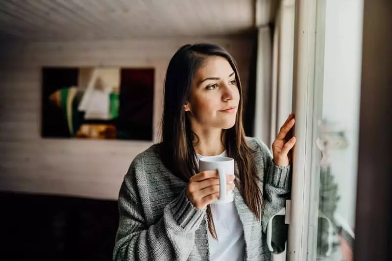femme qui regarde par sa baie vitrée
